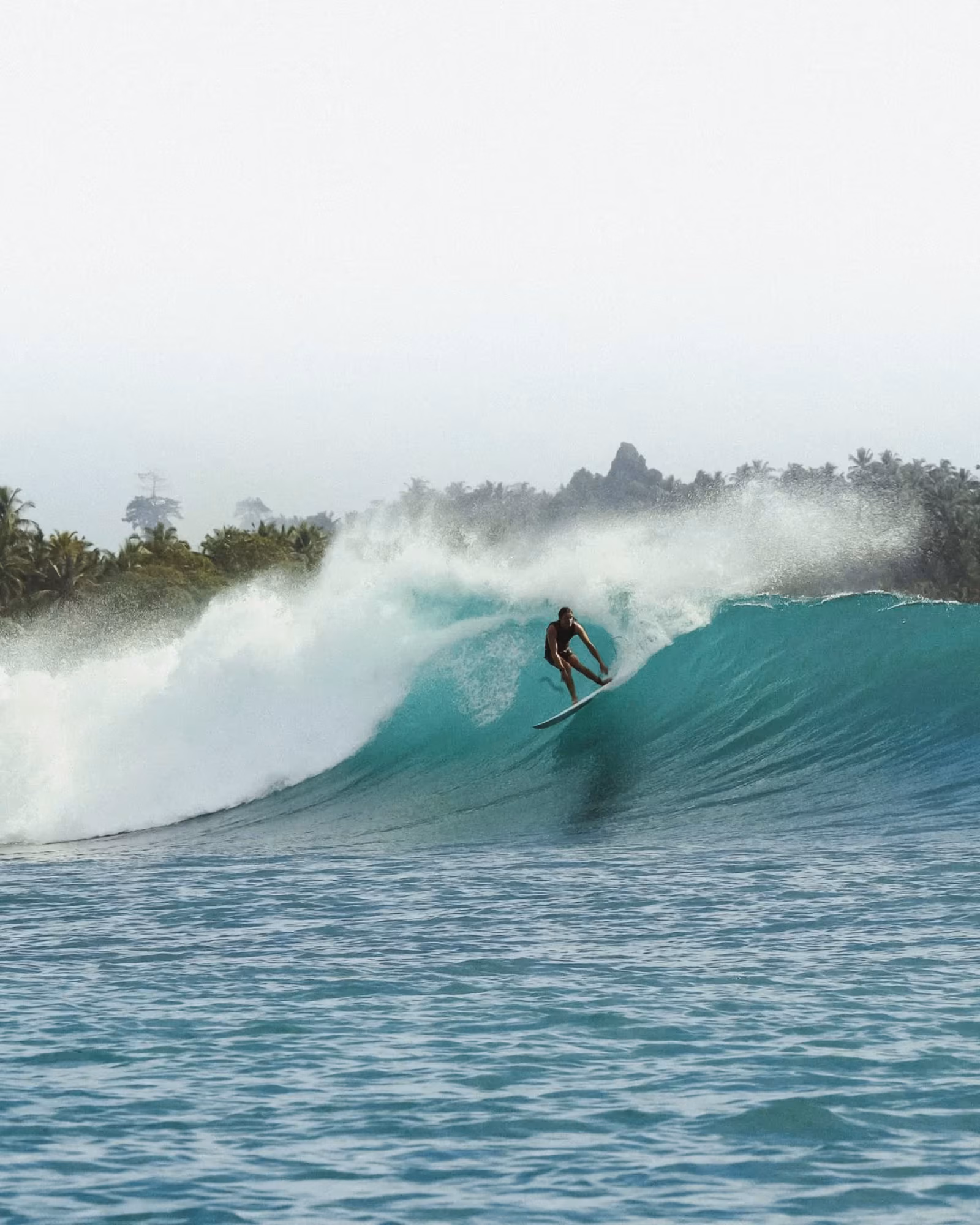 A surfer riding a turquoise wave