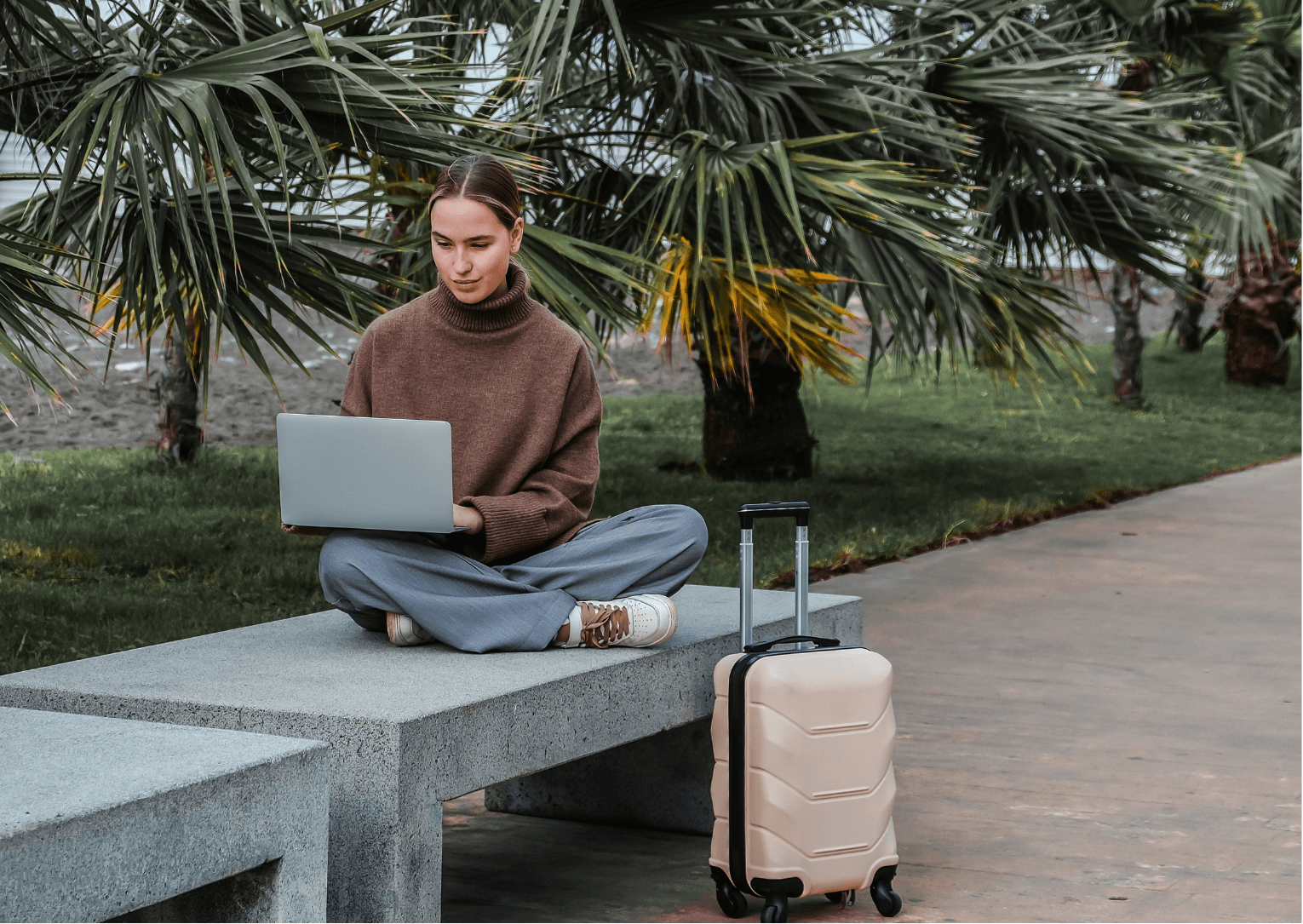 A girl sitting outside making a direct booking on her laptop.