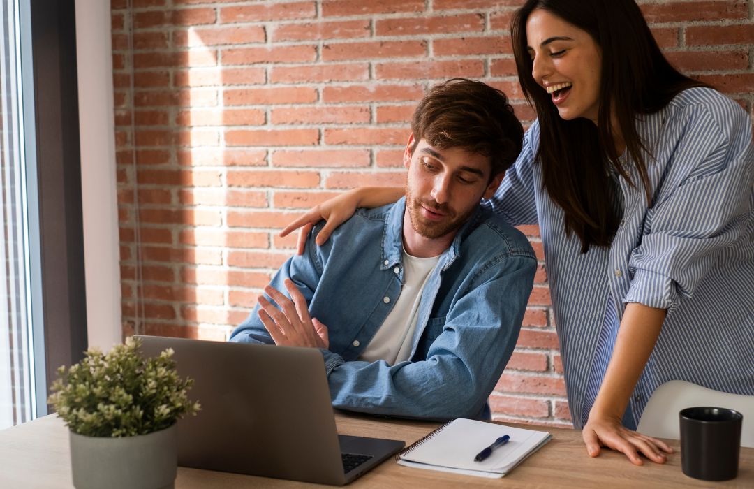 A couple improving their hotel SEO on a laptop.