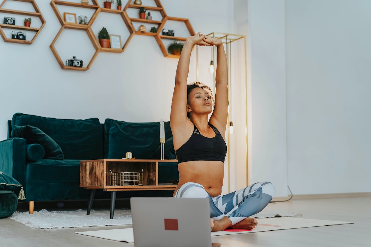 A women taking a live online yoga class from her living room. 
